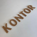 Bogstaverne "KONTOR" på flade overflade, ser ud som kork.