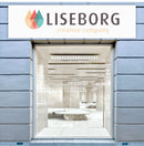 Rektangulært facadeskilt med logo og tekst "Liseborg creative company" over indgang med glasvinduer.