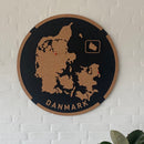 Rundt vægpanel med Danmarkskort udskåret i kork på mørk baggrund; "DANMARK" står nederst.