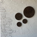 Fire brændte korkcirkler i forskellige størrelser på en lys væg, arrangeret i et mønster.