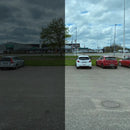 Parkeringsplads splittet i to; venstre side mørkere, højre side klarere med biler og bygning.