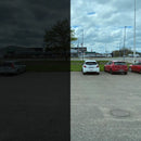 Billedet viser en parkeringsplads med biler. Venstre side er mørkere, højre side lysere.