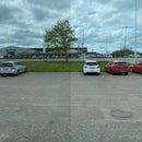 Venstre side er mørkere; højre side klarere med bedre udsyn til parkeringsplads og skyet himmel.