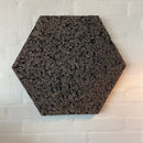 Sekskantet korkplade med ru tekstur, monteret på en væg. Velegnet som dekorativt element.