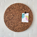 Rund korkcirkel på hvid væg med fastgjort kort af farverige geometriske fugle.