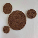 Fire runde korkcirkler i forskellige størrelser på en tekstureret baggrund.