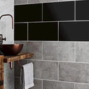 Sorte foliefliser på badeværelsesvæg med refleksion, kontrast til naturlige fliser.