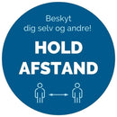 Blå cirkel med teksten "Beskyt dig selv og andre! HOLD AFSTAND" og to figurer med pil imellem.