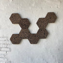 Mørke, sekskantede korkfliser arrangeret på en væg i et geometrisk mønster.