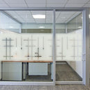 Frostet glasvæg med sandblæst geometrisk mønster, lodrette og vandrette linjer, semi-transparent.