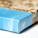 En blå lærredsprint med en glat overflade og en skarp kant. Baggrunden er sløret og brunlig.