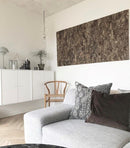 Dekorativ korkbark på væg over hvidt skab ved siden af stol. Grå sofa med puder foran.