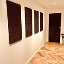 Fire mørke, rektangulære paneler på væggen i en gang med lyst parketgulv.