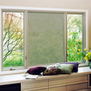 Vindue med tre ruder, midterste dækket af folie. Vinduesbænk med puder og blomster.