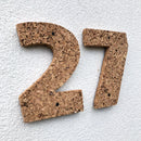 Korknumrene "2" og "7" med ru overflade, fastgjort med skruer på en udvendig væg.