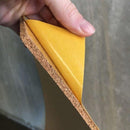 Nærbillede af hånd, der holder korkpanel med aftageligt lag. Korken ser grov ud.