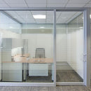 Kontor med glasvægge og sandblæst film i vandrette striber, der giver privatliv og lysgennemgang.