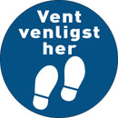Rund gulvfolie med to hvide fodaftryk og teksten "Vent venligst her" på blå baggrund.